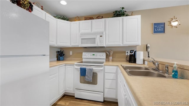 kitchen with white appliances, a sink, white cabinets, and light countertops