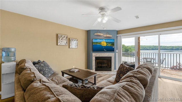 living area featuring a ceiling fan, light wood finished floors, and a fireplace