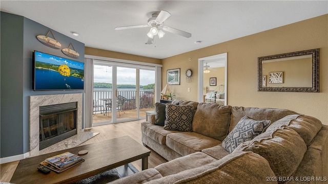living area featuring a ceiling fan, a premium fireplace, and wood finished floors
