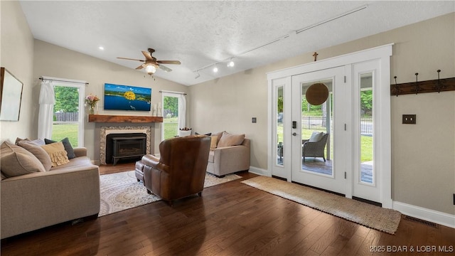 living room featuring ceiling fan, dark wood-style flooring, baseboards, lofted ceiling, and a fireplace