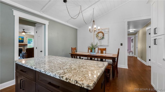 dining space with lofted ceiling, dark wood-style flooring, a chandelier, a ceiling fan, and baseboards