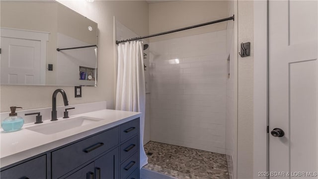 bathroom featuring tiled shower and vanity