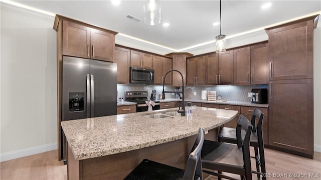 1045 Topsider Ln Unit 314, Osage Beach, MO 65065 - kitchen featuring appliances with stainless steel finishes, baseboards, light wood-style floors, backsplash, and a center island with sink