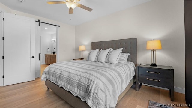 1045 Topsider Ln Unit 314, Osage Beach, MO 65065 - bedroom featuring a barn door, light wood-type flooring, ensuite bathroom, and a ceiling fan