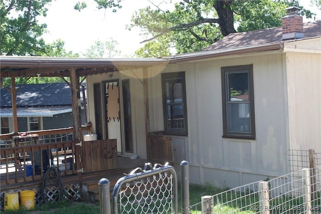 exterior space featuring fence, a chimney, and a deck