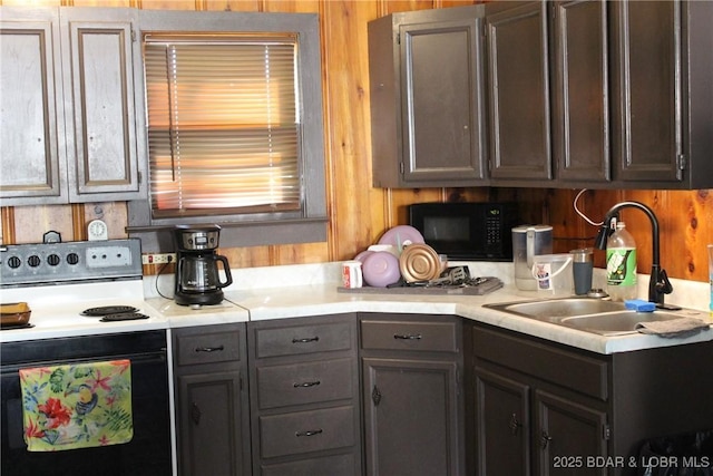kitchen featuring electric range, black microwave, light countertops, and a sink