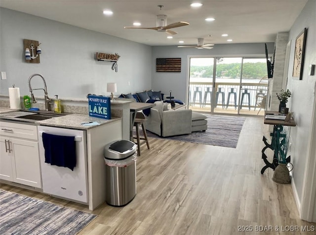 1481 Ledges Dr Unit 1019, Osage Beach, MO 65065 - kitchen featuring a sink, open floor plan, light wood-style flooring, ceiling fan, and white cabinetry