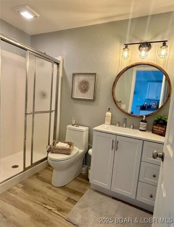 1481 Ledges Dr Unit 1019, Osage Beach, MO 65065 - bathroom featuring wood finished floors, toilet, a shower stall, a textured wall, and vanity