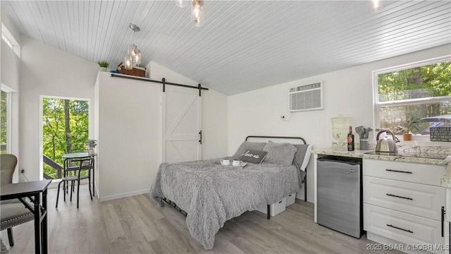 115 Hacksaw Ln, Camdenton, MO 65020 - bedroom with stainless steel fridge, a barn door, a wall mounted AC, light wood-style floors, and multiple windows