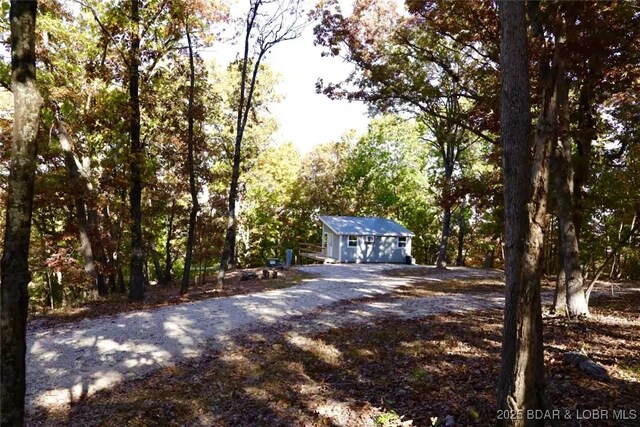115 Hacksaw Ln, Camdenton, MO 65020 - view of front facade with driveway, an outbuilding, and a wooded view