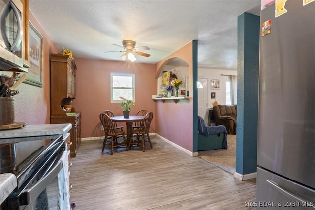 dining room featuring ceiling fan, light wood-style flooring, and baseboards