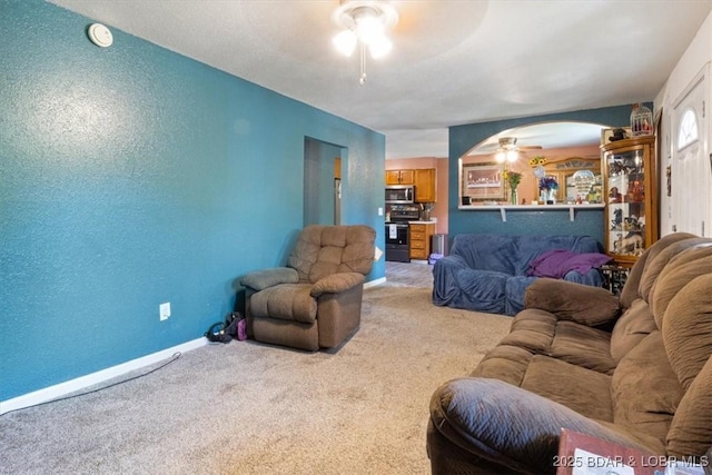 carpeted living area featuring a ceiling fan and baseboards