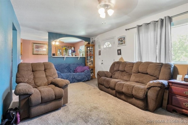 living area with a ceiling fan and arched walkways