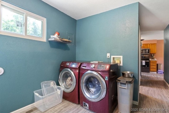 washroom with washing machine and clothes dryer, wood finished floors, and baseboards