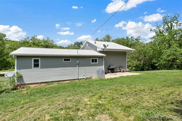 rear view of property featuring a yard and metal roof