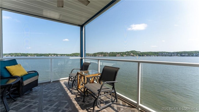 balcony featuring a water view, ceiling fan, and a sunroom