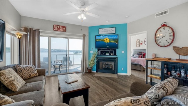living room featuring ceiling fan, wood finished floors, a fireplace with flush hearth, and baseboards