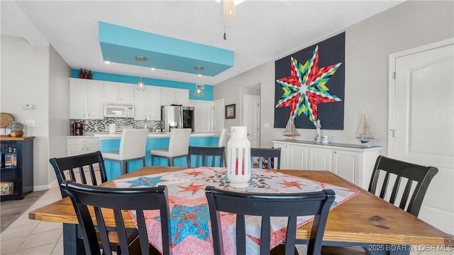 dining area with light tile patterned floors and a tray ceiling