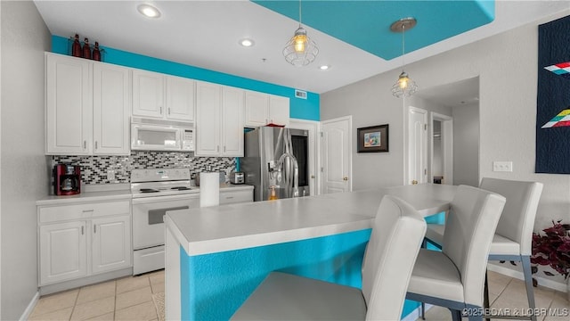 kitchen featuring white appliances, a breakfast bar area, decorative light fixtures, light tile patterned flooring, and recessed lighting