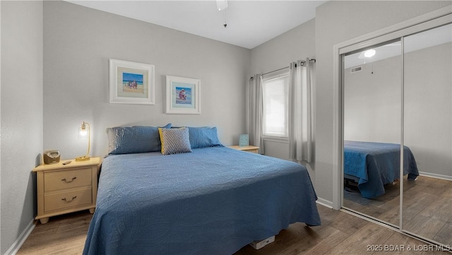 bedroom with wood finished floors, a closet, and baseboards
