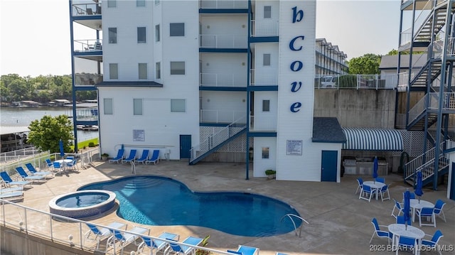 view of swimming pool featuring stairway, a pool with connected hot tub, a patio, and fence