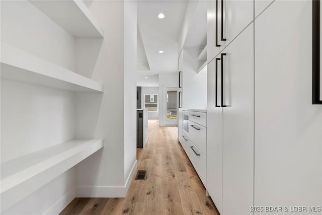 corridor with light wood finished floors, baseboards, and recessed lighting