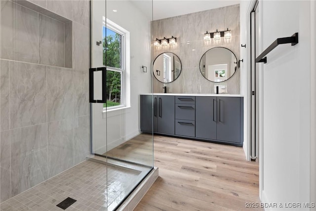 full bathroom with wood finished floors, double vanity, and an enclosed shower