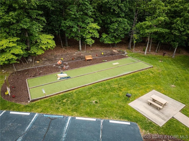 surrounding community featuring a game area, a lawn, and uncovered parking