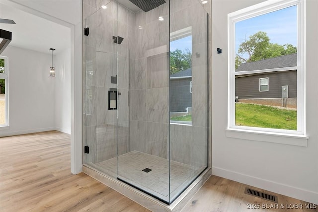 bathroom with baseboards, wood finished floors, and a stall shower