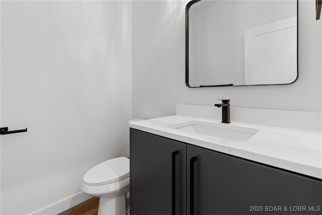 bathroom featuring vanity, wood finished floors, toilet, and baseboards
