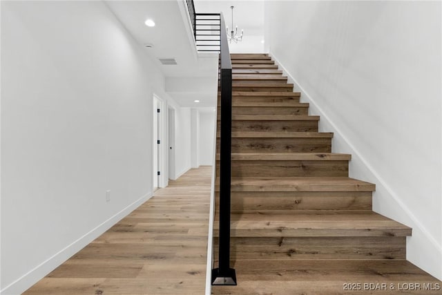 stairs with wood finished floors, recessed lighting, and baseboards
