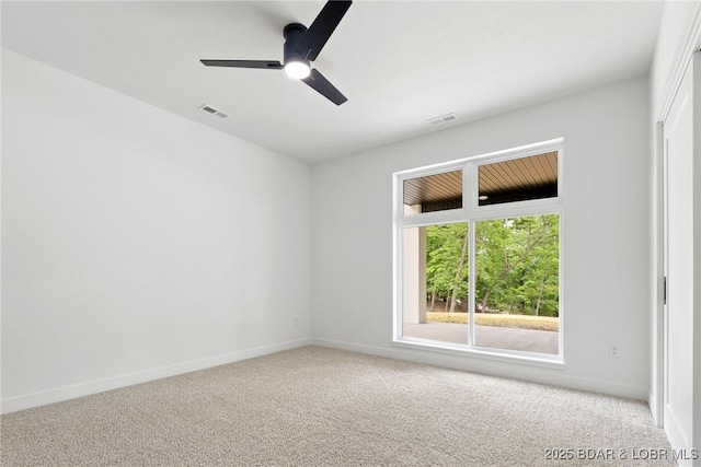 carpeted empty room with ceiling fan and baseboards