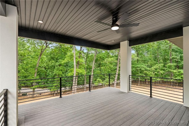 deck with ceiling fan and view of scattered trees