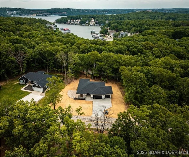 view from above of property with a heavily wooded area and a large body of water