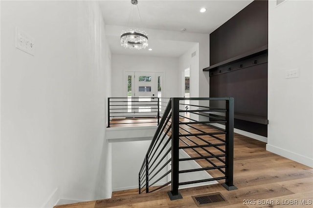 stairs with a chandelier, wood finished floors, recessed lighting, and baseboards
