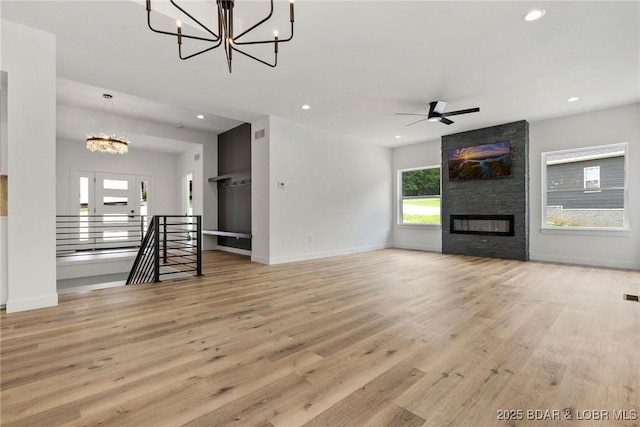 unfurnished living room featuring a chandelier, healthy amount of natural light, wood finished floors, recessed lighting, and baseboards