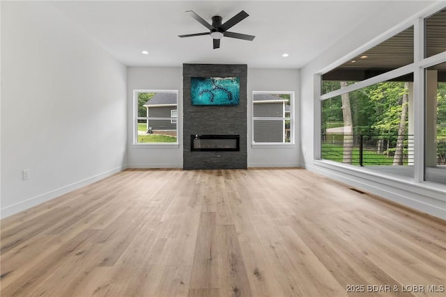 unfurnished living room with a ceiling fan, wood finished floors, a large fireplace, baseboards, and recessed lighting