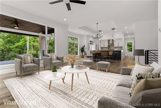living room with a chandelier, light wood finished floors, ceiling fan, and recessed lighting