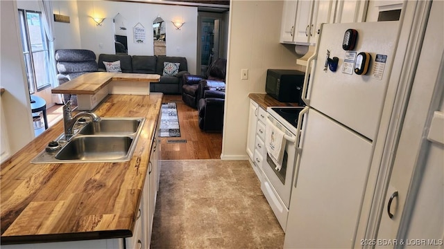 kitchen featuring wooden counters, a sink, white appliances, open floor plan, and white cabinetry