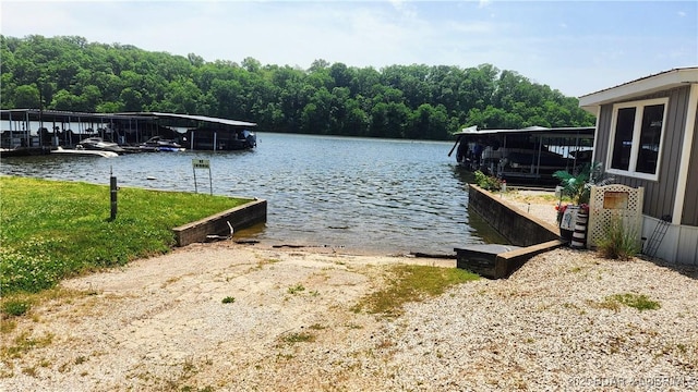 dock area with a water view, a boat ramp, and a forest view