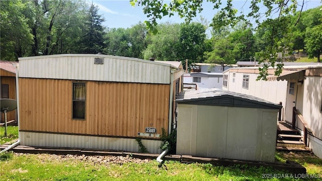 view of home's exterior featuring a storage shed, an outbuilding, and view of scattered trees