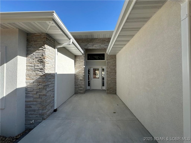 doorway to property featuring stone siding and stucco siding