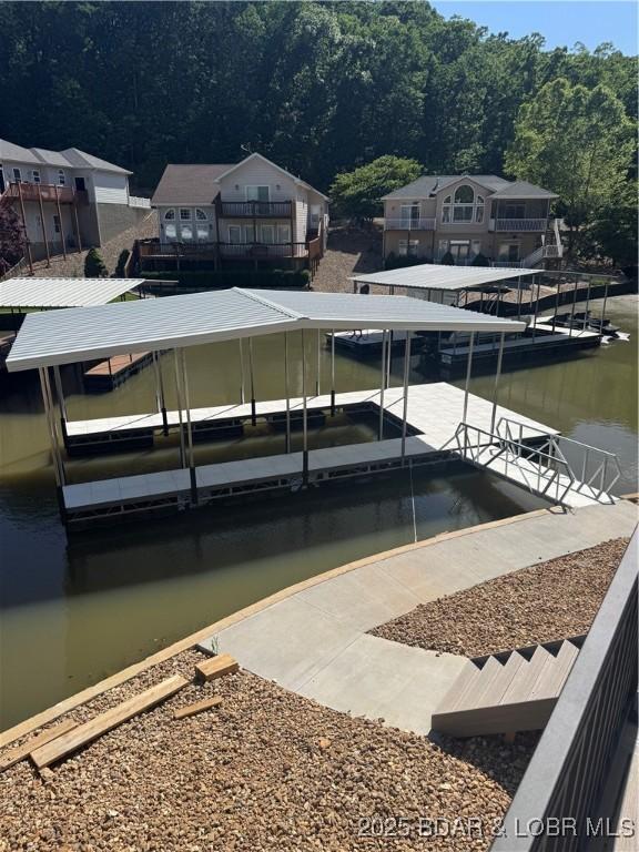 dock with a water view, boat lift, and a forest view