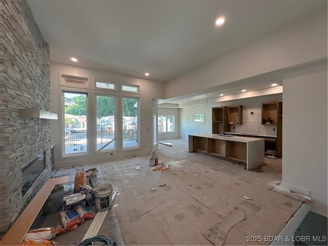 unfurnished living room featuring a stone fireplace and recessed lighting