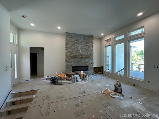 unfurnished living room with a stone fireplace, a towering ceiling, and recessed lighting