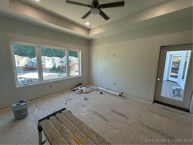 empty room with plenty of natural light, a raised ceiling, baseboards, and ceiling fan