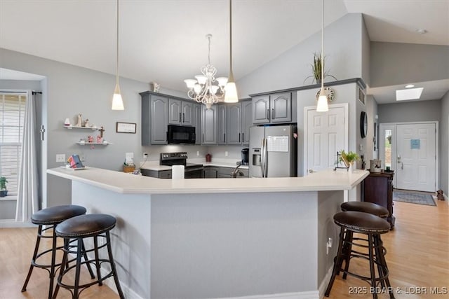 5183 Vicus Castri, Osage Beach, MO 65065 - kitchen with appliances with stainless steel finishes, gray cabinetry, a kitchen breakfast bar, vaulted ceiling, and light wood-type flooring
