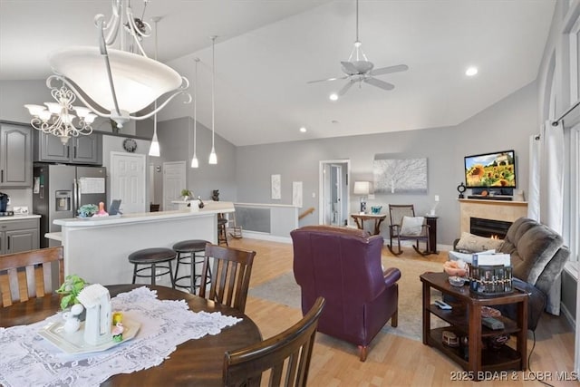 5183 Vicus Castri, Osage Beach, MO 65065 - dining room featuring a ceiling fan, light wood-style floors, baseboards, a lit fireplace, and high vaulted ceiling