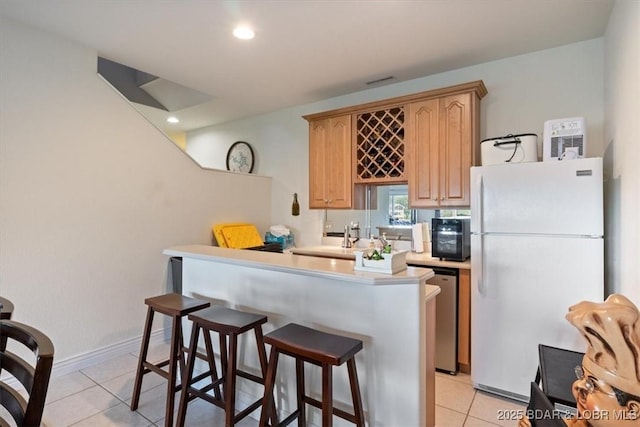 5183 Vicus Castri, Osage Beach, MO 65065 - kitchen featuring freestanding refrigerator, light tile patterned floors, a breakfast bar, light countertops, and dishwasher