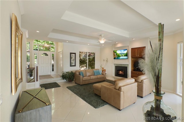 5482 Stoneledge Cir, Osage Beach, MO 65065 - living room featuring a tray ceiling, a warm lit fireplace, light tile patterned floors, recessed lighting, and ceiling fan